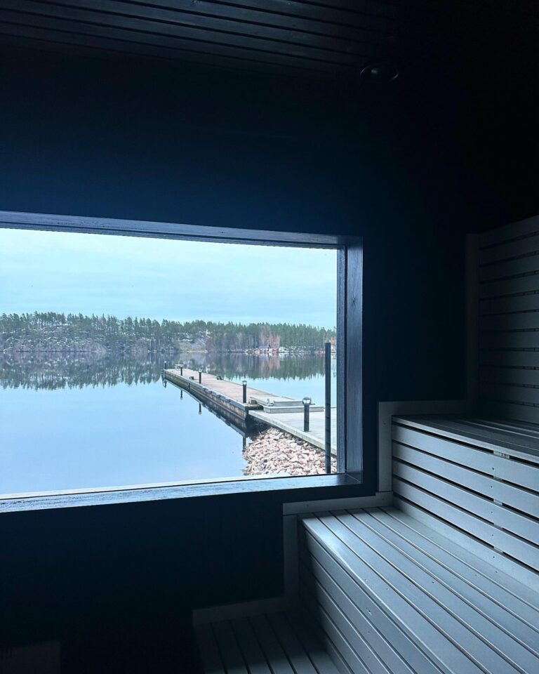 Bastuns lavar framför ett panoramafönster med utsikt över bryggan och sjön