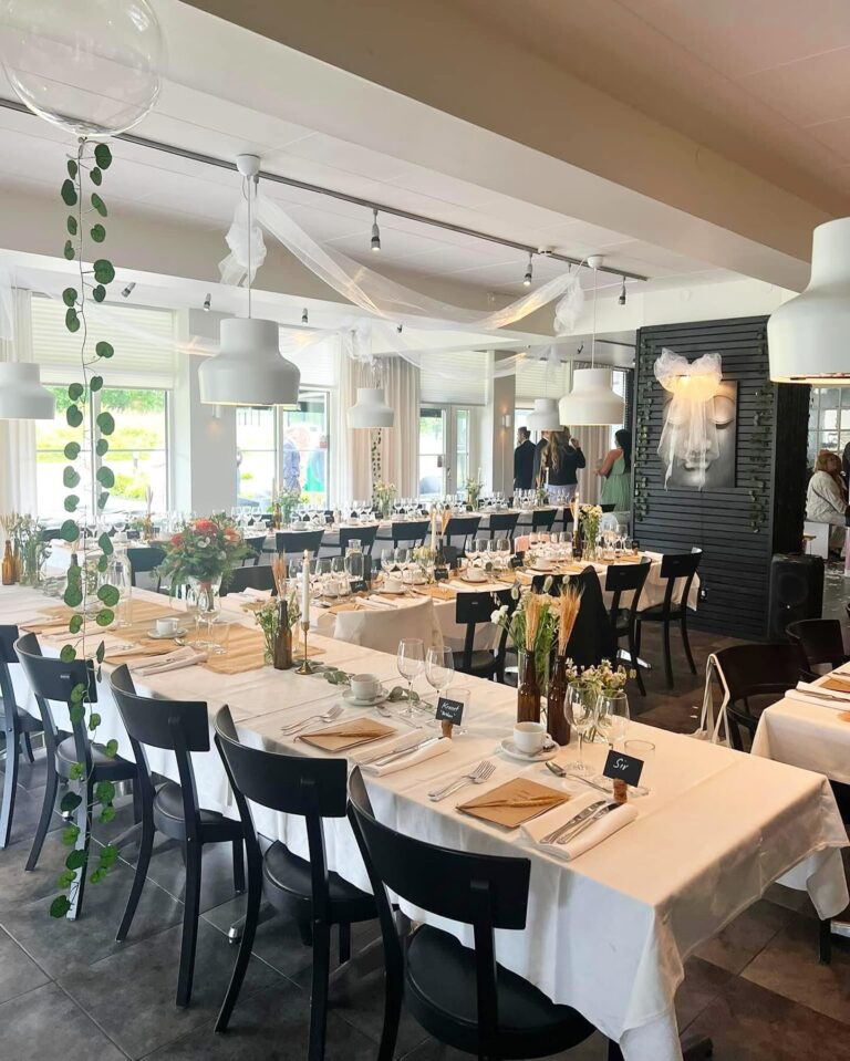 Bröllopsdukade långbord med draperier och blomsterarrangemang i salen