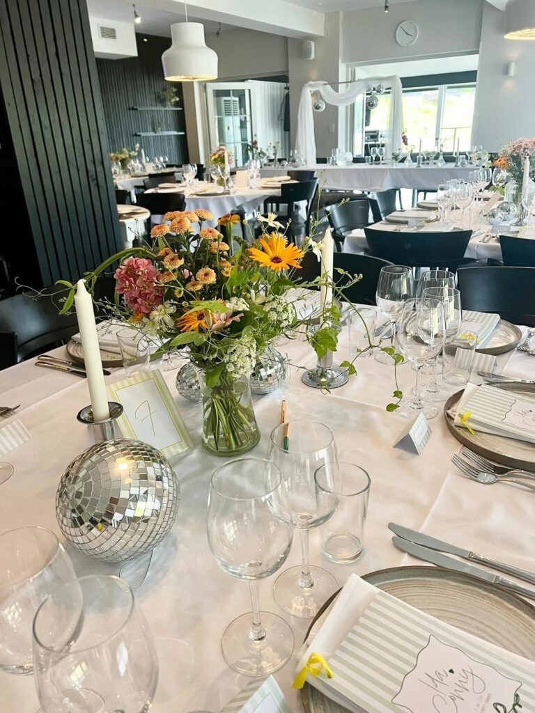 Festdukat bord med sommarblommor, levande ljus och discokulor