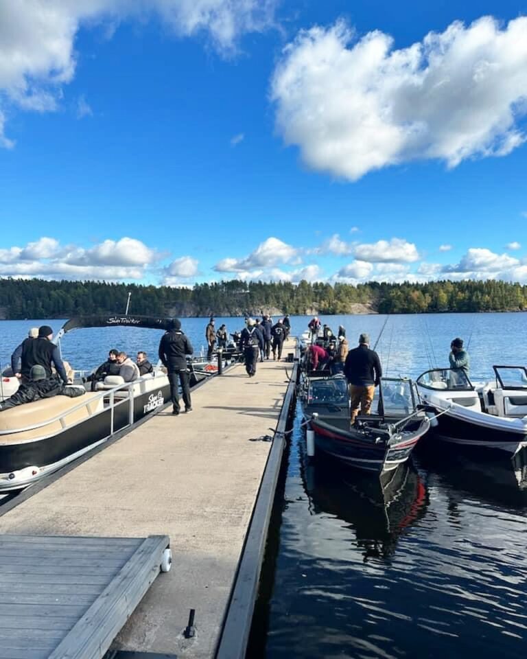 Fiskebåtar och deltagare längs bryggan under en fisketävling en höstdag