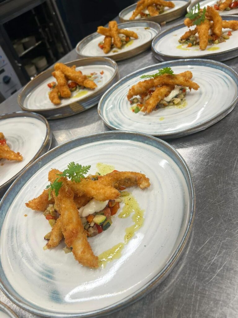 Friterad fisk på grönsakssalsa med aioli och örtolja, uppdukat på flera fat