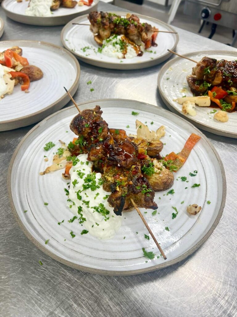 Grillspett med glaze serverat med örtsås, färskpotatis och grillade grönsaker