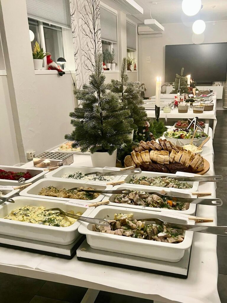 Långt julbord med sillbord, bröd och granar i vinterdukad sal