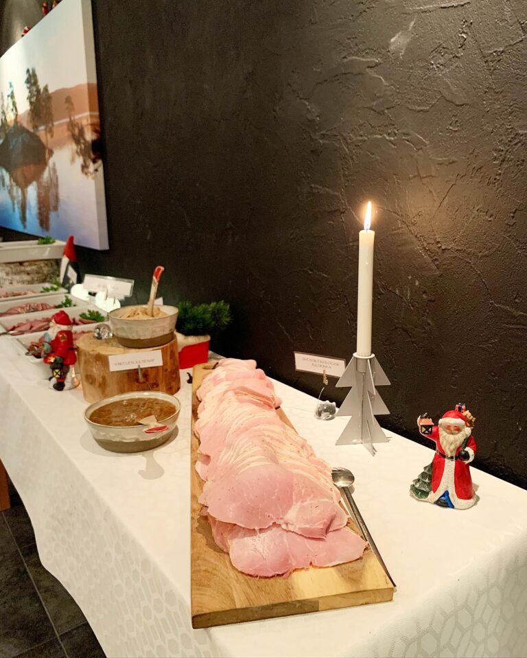 Skivad julskinka på skärbräda med hemrörd senap och levande ljus