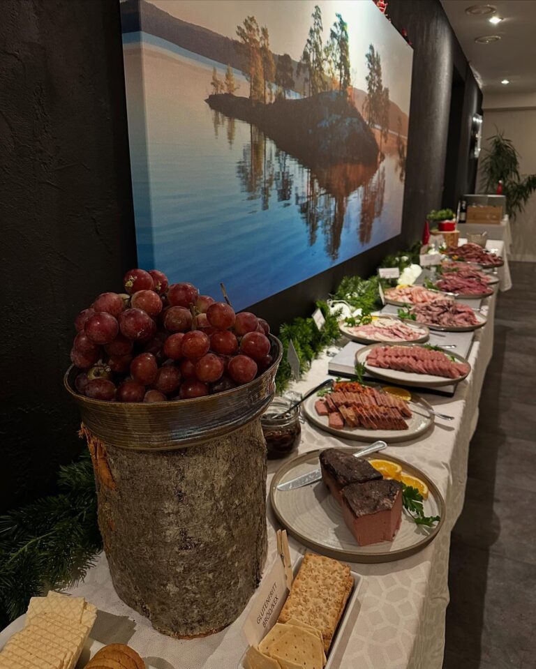 Julbord med leverpastej, ostar, druvor och charkfat längs ett långt bord