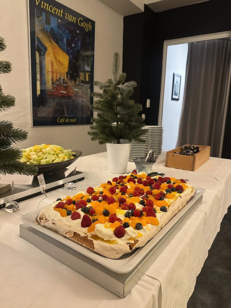 Stor marängtårta med grädde, hallon, blåbär och apelsinklyftor på dessertbordet