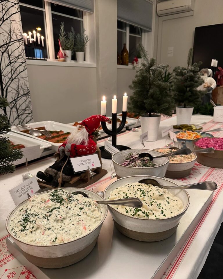 Skålar med hemgjord potatissallad och skaldjursröra på julbordet, med tomte och levande ljus