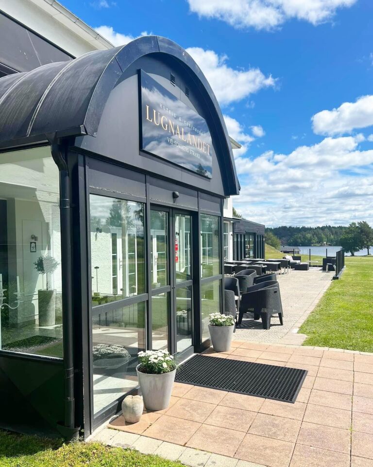 Lugnalandets entré med välvt tak och uteservering, med sjön Sommen i bakgrunden