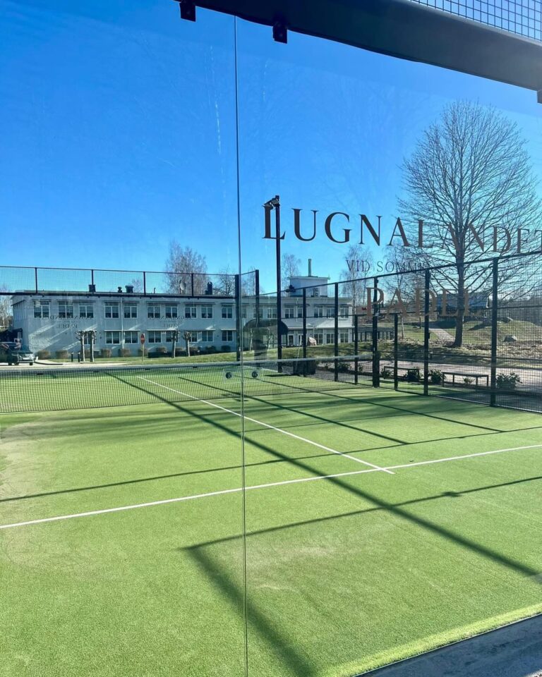 Utomhusbana för padel med glasväggar och hotellet i bakgrunden