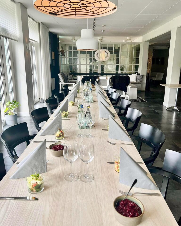 Dukat långbord i restaurangen med ljusa möbler och stora fönster