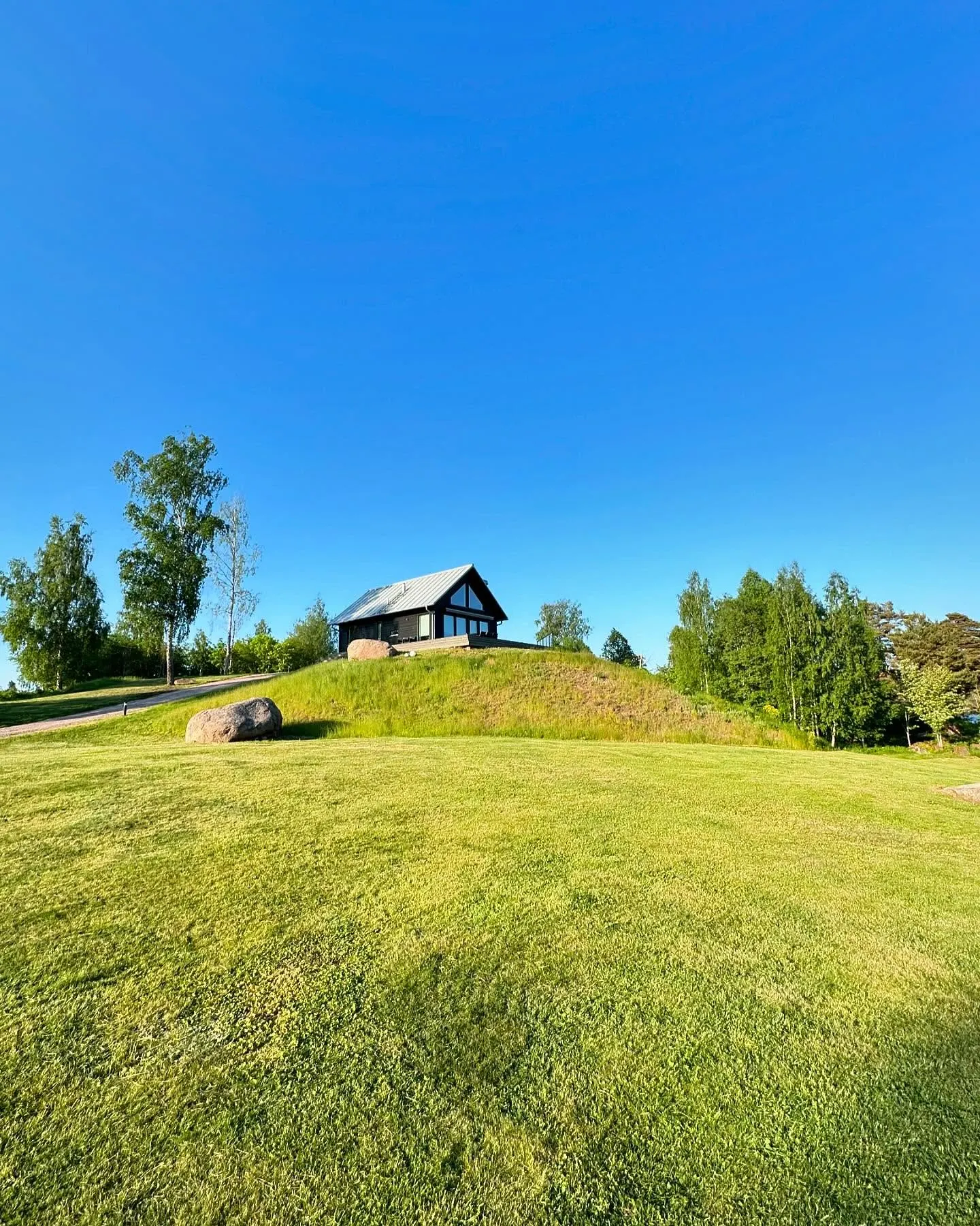 Storstugan with its large windows at the top of a grassy hill