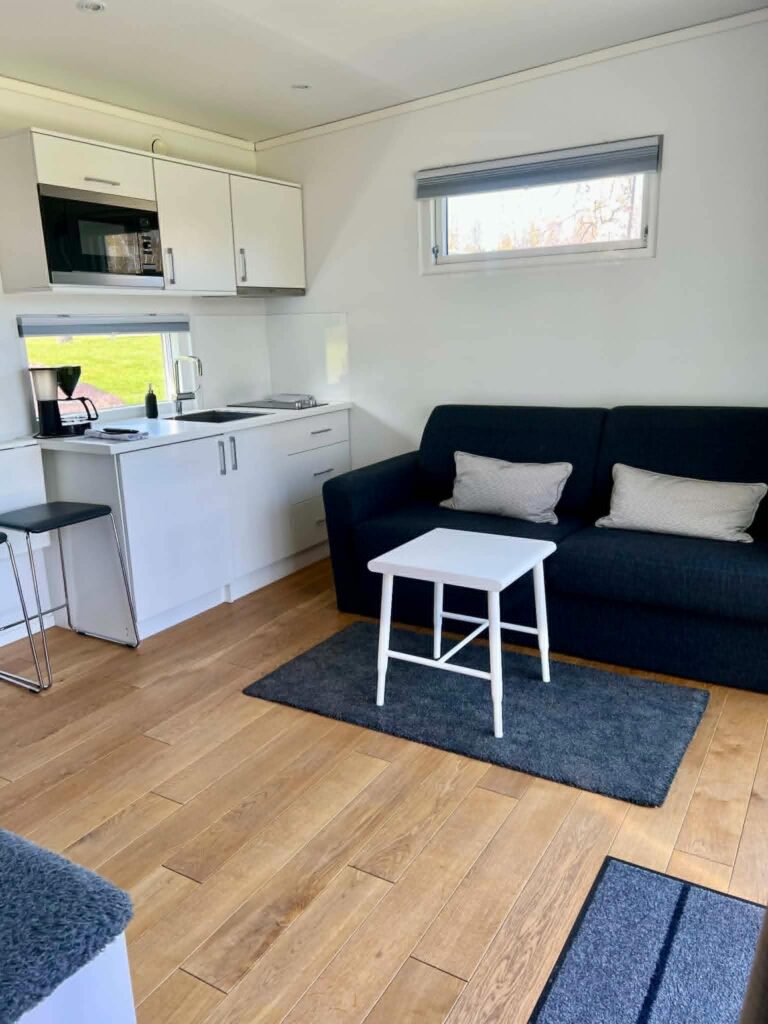 Ljust pentry med spishäll och mikro intill en mörkblå bäddsoffa